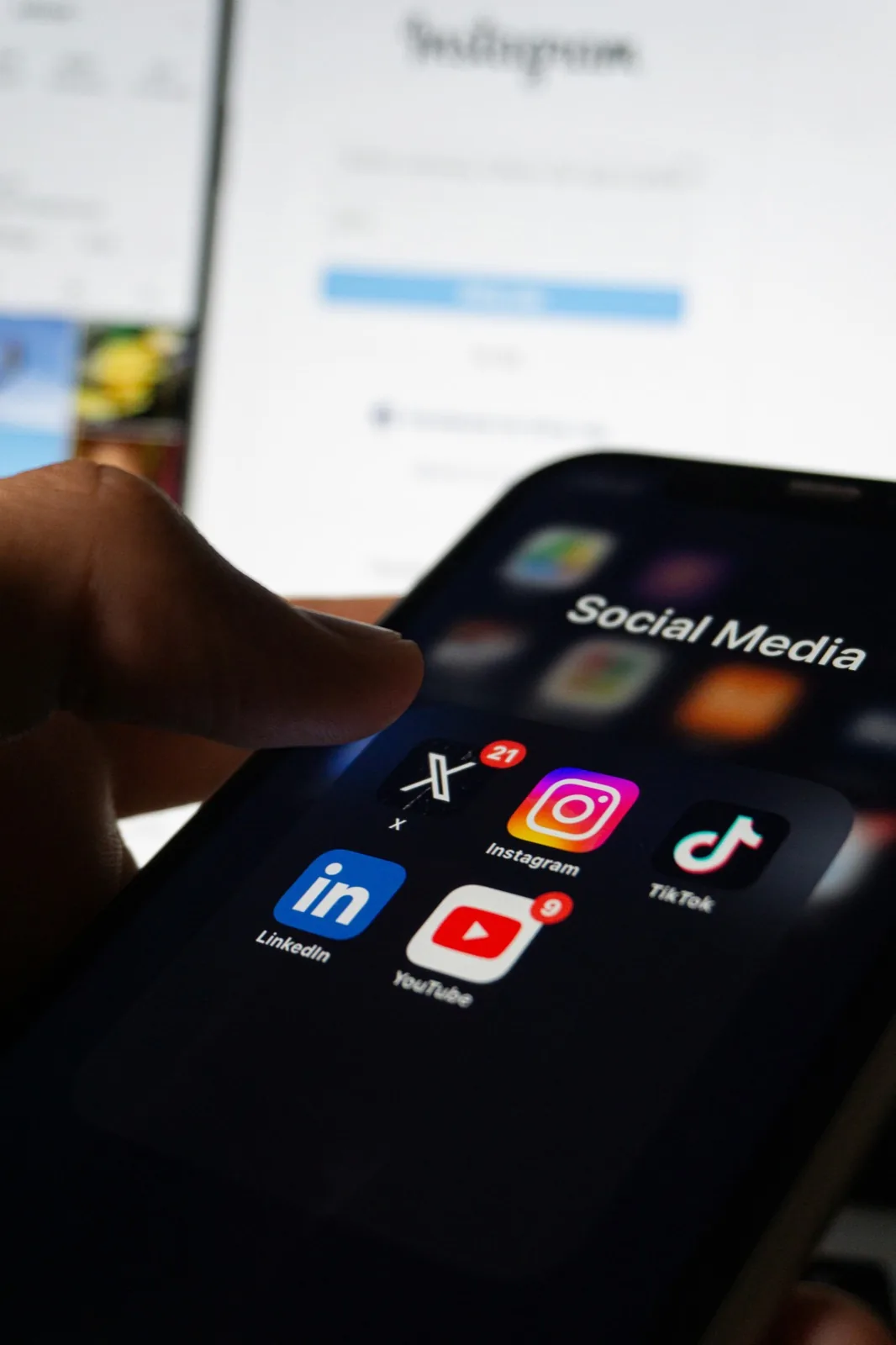 Smartphone mit Social-Media-Apps vor einem Laptop
